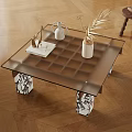 Modern Glass Top Coffee Table with Patterned Legs on Wooden Floor Featuring Vase and Book