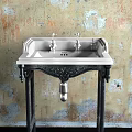 Vintage Washbasin With Double Silver Faucets And Carved Black Stand Against Textured Wall