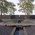 Serene Feature Wall In Garden With Trees Stone Path Stream And Grass Area