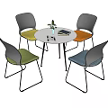 Round White Table with Four Colored Chairs Metal Legs Small Plant and Book