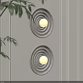 Round Striped Wall Lamps Mounted On Light Colored Paneled Wall With Green Plant Leaves