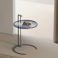 Modern Minimalist Side Table with Round Tempered Glass Top and Black Metal Frame Holding Magazine