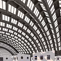 Modern Open Exhibition Hall with Arched Glass Roof White Walls and Displayed Artworks