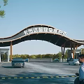 Scenic Entrance Gate with Curved Wooden Roof and Parking Area Featuring Cars and Pedestrians