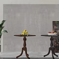 Wooden Side Tables With Carved Legs And Fruit Bowls Near Green Plant And Decorative Wall