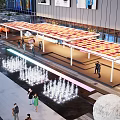 Modern Commercial Street With Glass Buildings Billboards Outdoor Seating Vehicles And Pedestrians