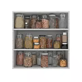 Various Grains Nuts and Spices in Glass Jars Neatly Arranged on White Kitchen Shelves