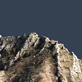 Scenic Mountain Landscape with Rocks Green Vegetation Red Roofed Building and Path Near Waterfront
