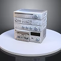 Stacked Electronic Audio Equipment With Knobs Buttons On White Round Platform