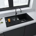 Modern Kitchen Black Sink With Running Faucet White Countertop Cutting Board Oranges And Gray Cabinets