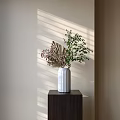 White Ribbed Vase With Greenery And Purple Flowers In Sunlit Shadows On Dark Wooden Cabinet