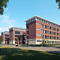Red Brick Multi Story School Building With Large Windows Greenery And Pedestrians On Campus