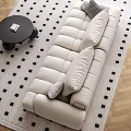 Beige Three-Seater Sofa With Plush Rounded Cushions White Walls Windows And Round Coffee Table
