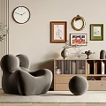 Gray Accent Chair with Framed Artworks Wall Clock Wooden Bookshelf Books Green Plant and Rug