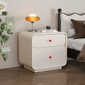 Cream Two Drawer Bedside Table With Red Knobs Orange Lamp Book And Green Plant 3d model