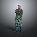 Military Soldier In Camouflage Uniform With Green Cap Standing Arms Crossed On Gray Background