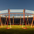 Circular Outdoor Art Installation Featuring Orange Swings White Stripes Green Grass And Mountain Backdrop