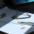 Elegant Fountain Pen Resting on Lined Notebook Paper with Necklace Seal and Laptop in Background