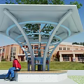 Outdoor Shelter With Tree And Person Sitting On Bench Near Red Brick Building