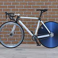 Stylish White Frame Bicycle With Blue Wheel Against Brick Wall And Wooden Floor