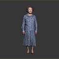A Woman In Blue Floral Dress Standing Against Gray Background Smiling With High Heels