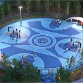 Outdoor Basketball Court With Blue Surface People Playing And Surrounding Trees