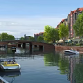 Scenic River Landscape With Stone Bridge Red Roofed Buildings Green Trees And Boats