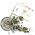 Transparent Glass Vase With White Flowers And Green Leaves Next To White Candles And Books
