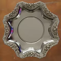 Silver Decorative Plate With Intricate Carved Edges And Shiny Surface On Wooden Background