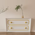 White Chest of Drawers With Gold Accents And Potted Plants Nearby