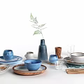 Stylish Dinnerware Set With Ceramic Plates Blue Bowls Wooden Trays Metal Utensils And Green Leaves