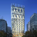 Tall Modern Skyscraper With Illuminated Geometric Glass Facade In Urban Cityscape