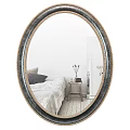 Oval Mirror With Gold And Black Frame Reflecting Bedroom Scene With Bedside Table And Vase