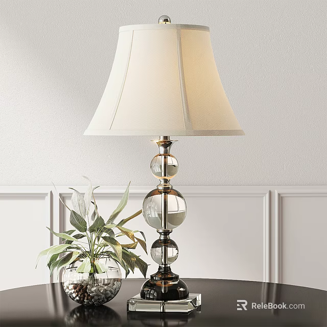 Ivory Lampshade Table Lamp with Glass Globe Base and Green Plant against White Wall Paneling 3d model 