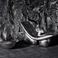 Unique Metallic Silver Leisure Chairs With Sculptural Design And Rock Wall Backdrop