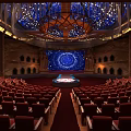 Luxurious Theater Interior With Red Seats Stage Blue Circular Backdrop And Ornate Ceiling Decorations