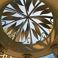 Ornate Circular Metal Ceiling With Leaf Patterns And Columns Against High Rise Buildings