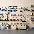 Organized Sports Equipment Arrangement on Wall Pegboard with Various Balls Rackets Dumbbells and Fitness Gear