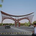 Modern Entrance Gate with Curved Steel Frame Central Logo Surrounded by Trees and Cars