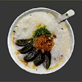 Savory Congee Topped with Century Egg Green Onions Chili Flakes in White Bowl with Spoon