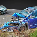Wrecked Blue Car And Another Damaged Vehicle At Traffic Accident Scene With Scattered Debris