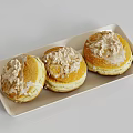 Three Tasty Donuts on White Tray Topped with Frosting and Crumbles