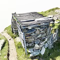 Traditional Stone And Wooden Hut Nestled In Grassy Natural Surroundings With Pathway And Greenery