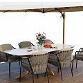 Oval Outdoor Table with Wicker Chairs and Beige Umbrella on Wooden Patio with Flower Vase