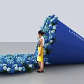 Woman Standing By Latrobe Blue Structure With Blue And White Flowers