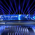 Large Event Venue With Blue Lighting Stage Backdrop Screen And Arranged Chairs