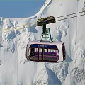 Scenic Cable Car Ride Over Snowy Mountain Peaks Under Clear Blue Sky