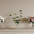 Transparent Glass Vases With White Roses Green Plants And Pink Orange Flowers On Light Shelf
