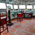 Ship Wheelhouse Interior With Wooden Chairs Tables Control Panels And Orange Floor