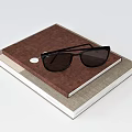 Brown Cover Notebook With Black Sunglasses On Stacked Books Light Background